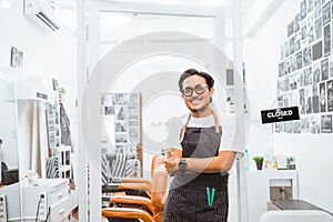 asian barber standing in front of barbershop with smiling face