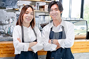 Asian barista or coffee maker man and woman stand with arm-crossed or confidence action also look to camera and smile in cafÃÂ© photo