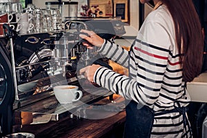 Asian barista woman making coffee cappuccino at cafe with machine at counter bar in eatery,Food and drink service concept