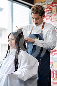 Asian beautiful customer woman sit and is processed of hairstyle by beauty salon barber man. Concept of beauty business for good