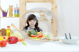 Asian beautiful kid girl cooking and cutting vegetables on kitchen, so happy and relax for leaning and education cook food.