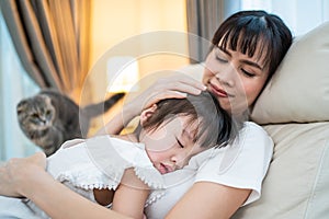 Asian beautiful loving mother hugging sleeping baby girl in her arms with gently. Parent holding small baby to rest on shoulder an