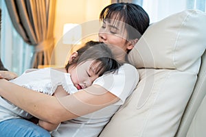 Asian beautiful loving mother hugging sleeping baby girl in her arms. Parent hold small baby to rest on shoulder with gently and
