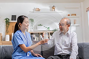 Asian beautiful therapist doctor serve milk to older patient in nursing home. Asian nurse in blue uniform assist elderly senior