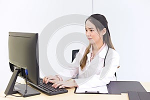 Asian beautiful woman doctor is typing on a keyboard to save information on the computer. New normal and healthcare concept