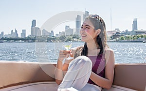 Asian beautiful woman drinking white wine and making toast while traveling and sitting on boat with background of beautiful