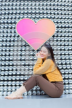 Asian beautiful woman with long hair is sitting and closing her eyes in heart background .