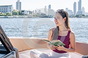 Asian beautiful woman reading book while traveling and sitting on boat with background of beautiful lanscape. Summer Travel and