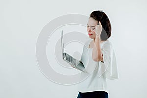 Asian beautiful woman Standing in a white shirt in her hand Holding a laptop computer The expression is thinking about work. With