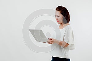 Asian beautiful woman Standing in a white shirt in her hand Holding a laptop computer Stand smiling happily With a white