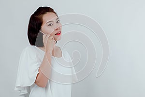 Asian beautiful woman Standing in a white shirt Put the mobile phone attached to the ear to talk to the destination. Prepare to