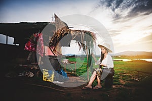 Asian Beautiful woman in Thai local dress sitting and working with fishing net in fishing village with field and lake