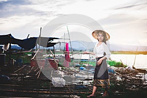 Asian Beautiful woman in Thai local dress working with fishing net in fishing village with field and lake background