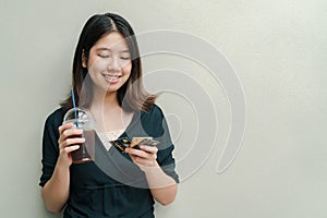 Asian beautiful woman Wearing a black shirt, standing drinking cold coffee in the hand And have a credit card in hand Happy face