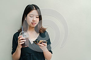 Asian beautiful woman Wearing a black shirt, standing drinking cold coffee in the hand And have a credit card in hand Happy face