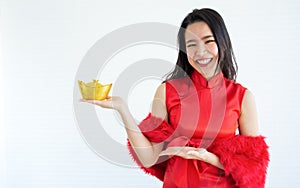 Asian beautiful woman wearing red dress or qipao, smiling with happiness, holding and presenting gold on hand to celebrate Chinese