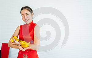 Asian beautiful woman wearing traditional red dress, smiling with happiness, holding and presenting gold on hand to celebrate