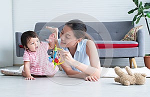 Asian beautiful young mother and Caucasian 7 months baby newborn girl playing with development toy and bear doll. Single mom lying