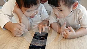 Asian beautiful young mother and her little daughters are enjoying playing games or entertaining using mobile apps on phone at hom