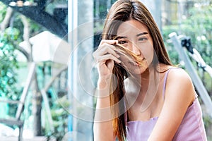 Asian beautiful young woman hand holding her long hair with looking damaged split ends of hair. Hair loss problem and Hair