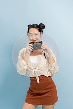 Asian beautiful young woman holding photo camera on blue background