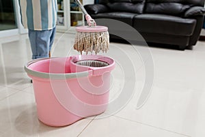 Asian beautiful young woman in protective gloves using a flat wet-mop while cleaning floor in the house, The housekeeper uses a