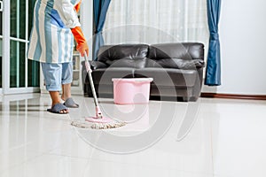 Asian beautiful young woman in protective gloves using a flat wet-mop while cleaning floor in the house, The housekeeper uses a