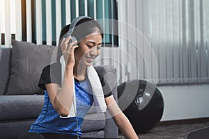 Asian beautiful young woman using laptop and headphones listen music while practicing exercise yoga at home