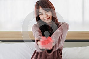 Asian beautifull woman holding red gift box and happiness in her bed room. Stay at home