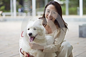 Asian beauty embracing her dog smiling at camera outdoor in garden