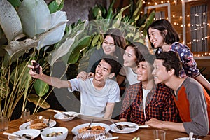 Asian bestfriend group take selfie with smartphone while having garden party