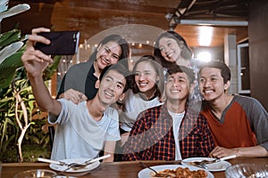 Asian bestfriend group take selfie with smartphone while having garden party