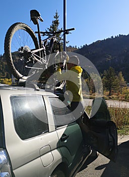 Asian biker man tying his bicycle on the car luggage-rack