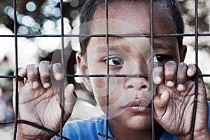 Asian boy against fence with sad expression