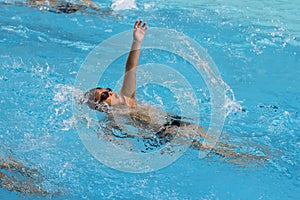 Asian boy back crawl swims in swimming pool