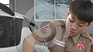 Asian boy in boy scouts uniform car washing at home, Thailand boy scouts helping your family at home.