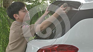 Asian boy in boy scouts uniform car washing at home, Thailand boy scouts helping your family at home.