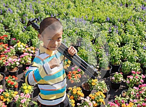 Asian boy carrying tripods standing in flower garden