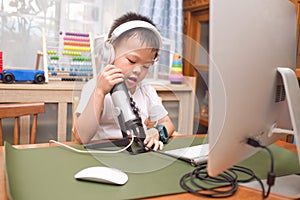 Asian boy child wearing headphones using microphone with computer prepare to making video call to relatives at home or making vlog