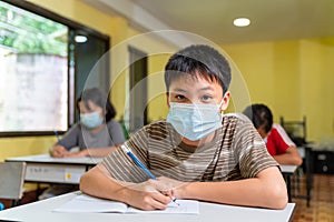 Asian boy in classroom with face mask back at school after covid-19 quarantine and lockdown