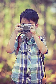 Asian boy with digital camera in beautiful outdoor. Retro style.