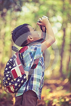 Asian boy with digital camera in beautiful outdoor. Retro style.