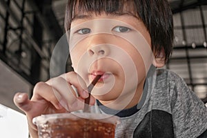 Asian Boy Drinks Iced Soda with a Straw