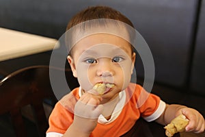 Asian boy is eating bread happily