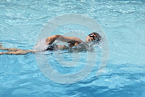 Asian boy front crawl swims in swimming pool