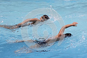 Asian boy front crawl swims in swimming pool