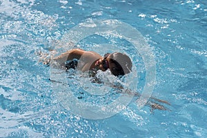 Asian boy front crawl swims in swimming pool