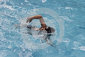 Asian boy front crawl swims in swimming pool