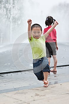 Asian boy and girl play by fountain