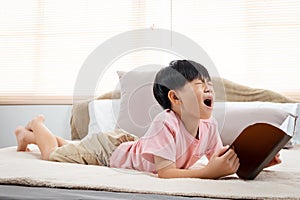 An Asian boy, handsome, laying in his favorite soft bed reading a book, He put the book down on the bed, and rubbing both eyes